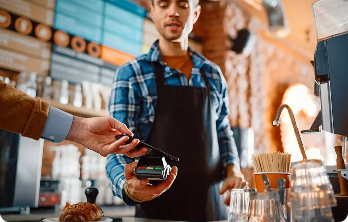 Un commerçant présente son DAB afin que le client puisse régler